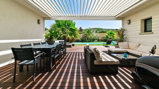 A covered outdoor patio with a dining table and chairs, a sofa, and a grill. - AIR-CONDITIONED VILLA WITH POOL IN PORTICCIO (Grosseto-Prugna)
