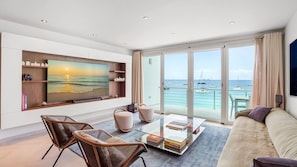 A modern living room with a large TV, comfortable seating, and a view of the sea and boats. - Luxurious 2BR/2.5BA Unit on Simpson Bay Beach (Simpson Bay)
