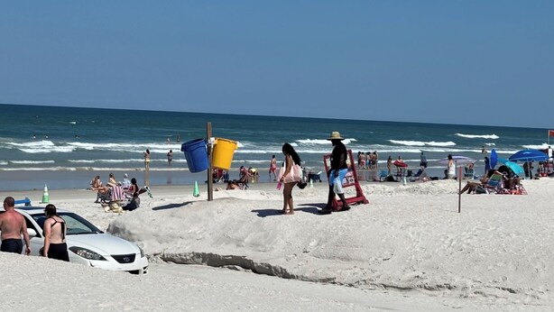A beach with people, a lifeguard tower, and a white car. - Spacious 4-bedroom house in serene Deltona with AC, WiFi (Deltona)