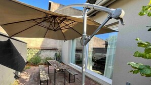 Un patio con una mesa, sillas, un toldo retráctil y una ventana.
