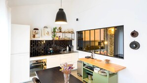 Una cocina moderna con una lámpara colgante negra, una mesa de comedor de madera y un armario verde.