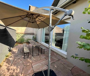 A patio with a table and chairs, a retractable awning, and a window.