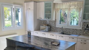 A modern kitchen with a central island, bar stools, and a window with curtains.