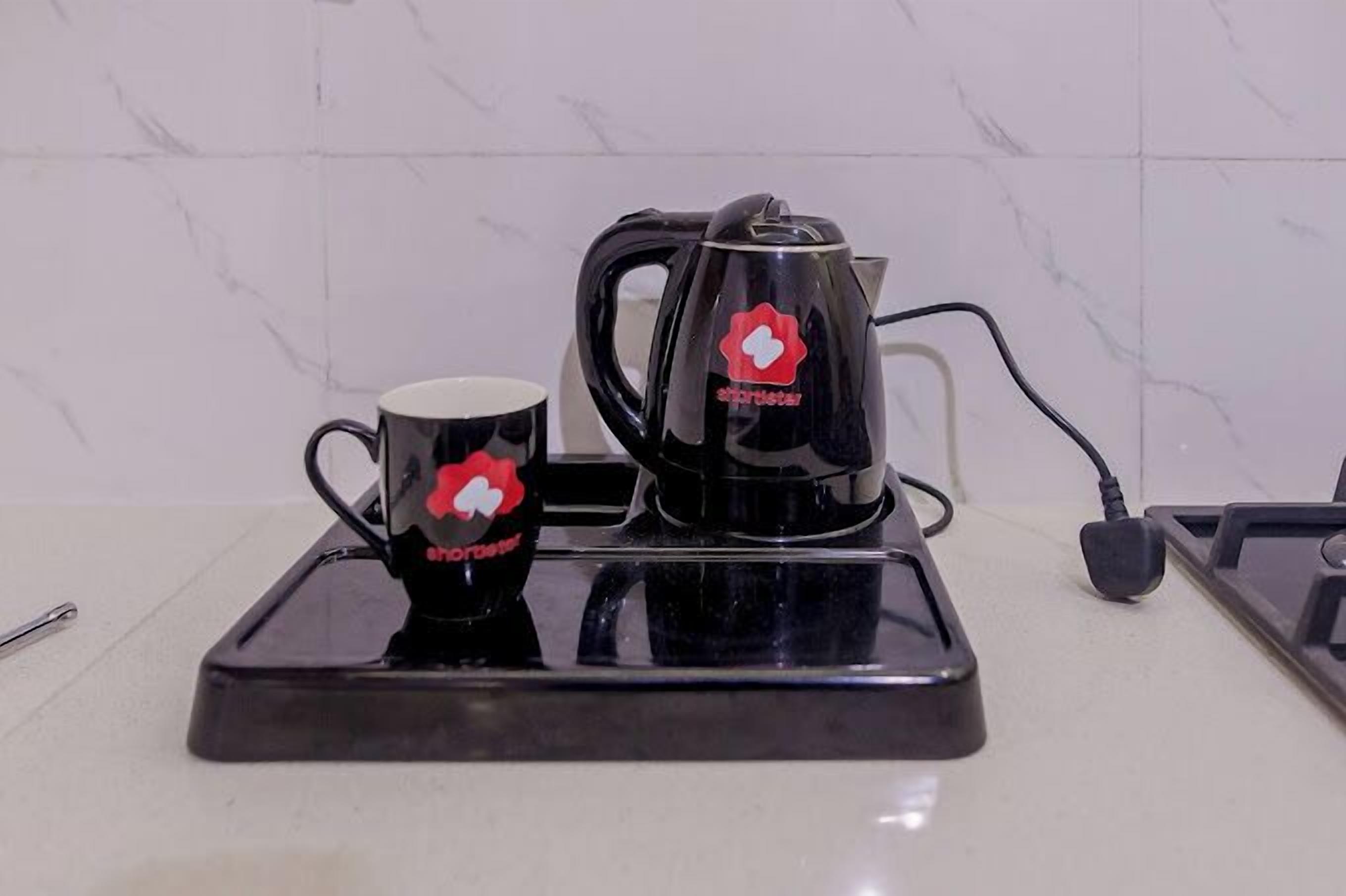 A kitchen counter with a coffee maker and a mug, both branded with a red logo.