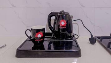 A kitchen counter with a coffee maker and a mug, both branded with a red logo.