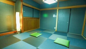 Una habitación con piso a cuadros, dos alfombras verdes, una puerta de madera y una l ámpara.
