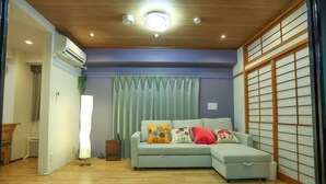 Una sala de estar con un sofá azul claro, techo de madera y un panel corredizo shoji.