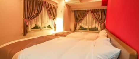 Una habitación de hotel con cama, cortinas, un equipo de aire acondicionado y una pared roja.