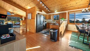 Una cocina moderna con armarios de madera, un refrigerador de acero inoxidable y un comedor con vistas.