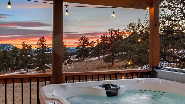 Un jacuzzi con vistas a una puesta de sol sobre un paisaje nevado.