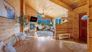 Interior acogedor de una cabaña con chimenea, paredes de madera y un televisor mostrando 'NETFLIX'.