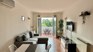 Un salon moderne comprenant un canapé, une table à manger, des chaises et un balcon avec une table et des chaises.