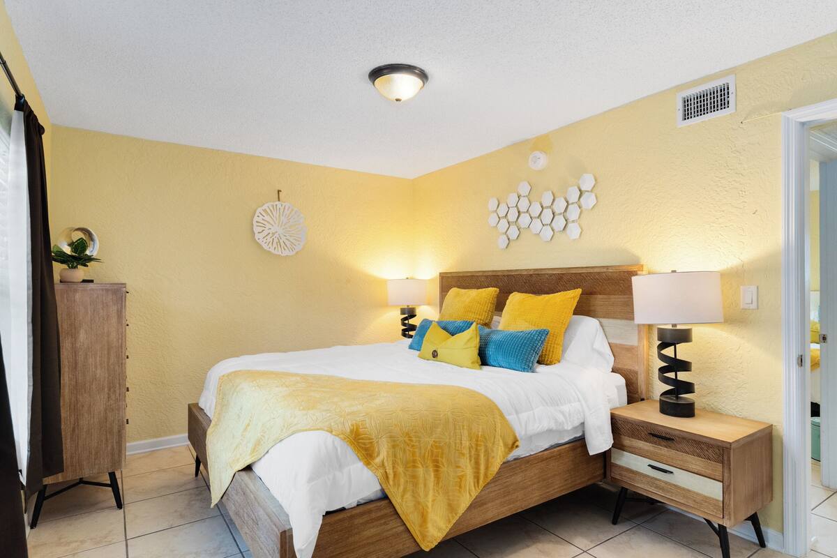Un dormitorio con cama, mesitas de noche, armario y decoración mural.