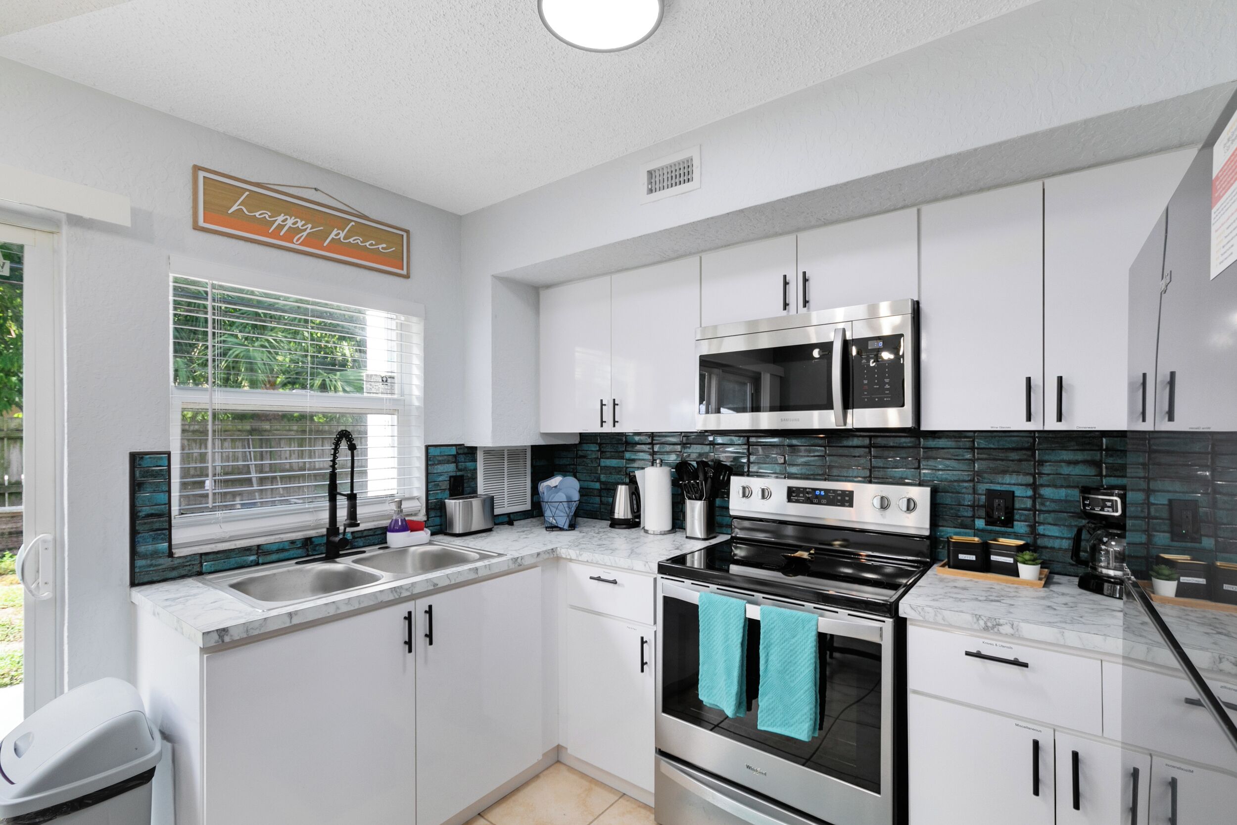 Una cocina moderna con armarios blancos, estufa de acero inoxidable y microondas.