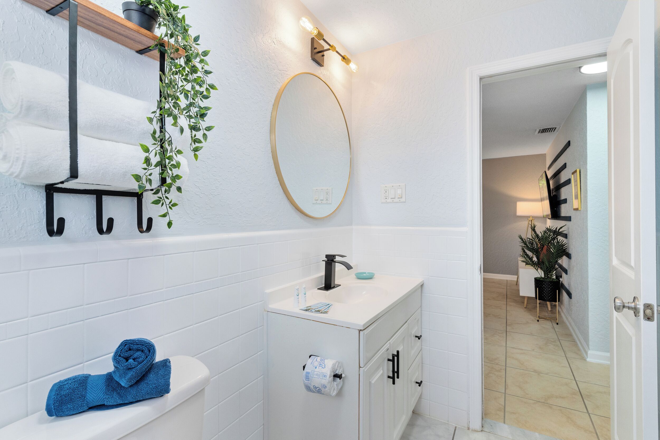 Un baño con lavamanos blanco, espejo, toallero y retrete.