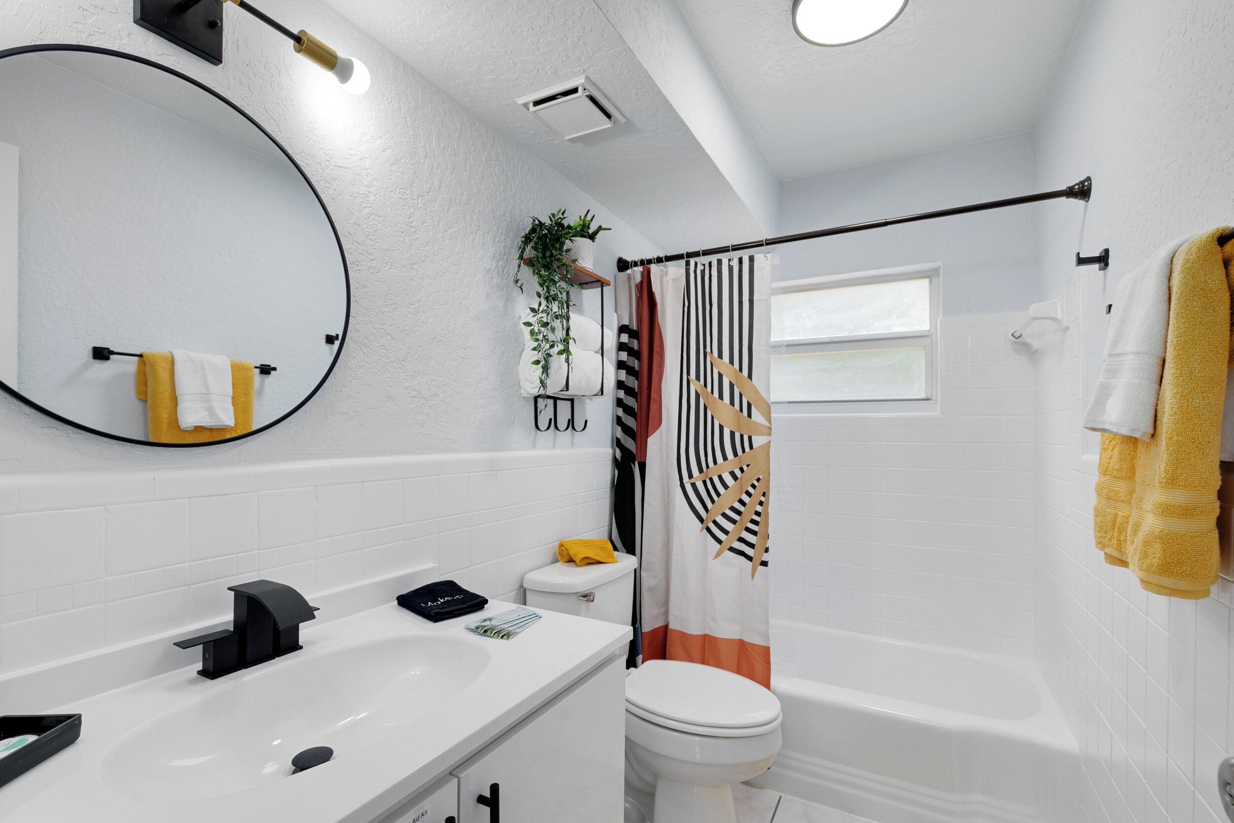 A modern bathroom with a white sink, black faucet, and a large mirror.