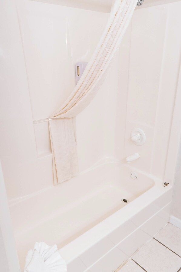 Un baño con bañera, cortina de ducha y toallero.