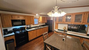 A kitchen with wooden cabinets, a stove, a sink, and a dining table with chairs.