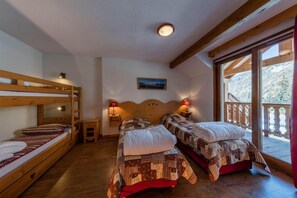 A room with two beds, wooden bunk beds, a small table, and a nightstand with lamps. - Resort center, swimming pool, parking, tv, ski locker, 27-54m², Abriès (Abriès)