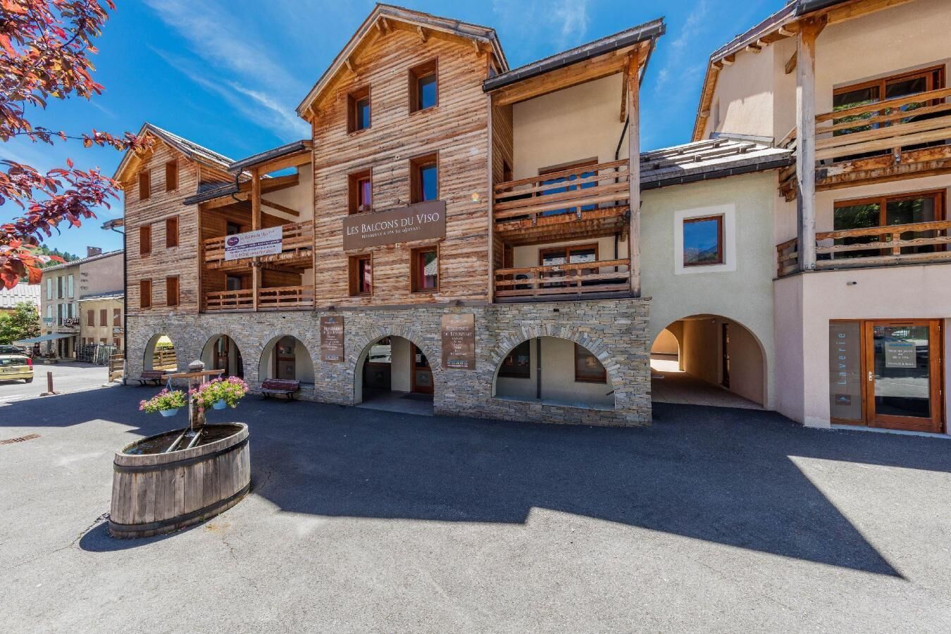 A wooden building with balconies and stone arches, labeled "Les Balcons du Viso."
