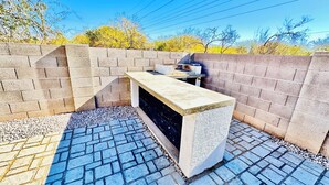 A small outdoor kitchen area with a countertop and a grill, surrounded by a brick wall and a paved floor. - Tucson two story 4BR  2.5BA house close to airport & major attractions Sleeps 8 (Tucson)