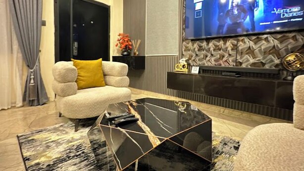 A modern living room with a sofa, a coffee table, and a flat-screen TV mounted on the wall. - Wedgewood One Shortlet Apartment (Ibadan)