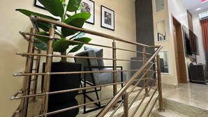 A staircase with a metal railing, a potted plant, a gray sofa, and a framed picture on the wall. - Wedgewood One Shortlet Apartment (Ibadan)