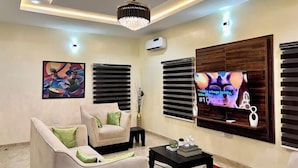 A modern living room with a sofa, a coffee table, and a TV mounted on the wall. - Wedgewood One Shortlet Apartment (Ibadan)