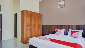 Une chambre bien rangée, avec un grand lit, une armoire en bois et un tableau encadré accroché au mur.