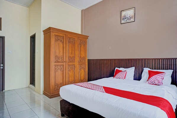 A neatly arranged bedroom with a large bed, a wooden wardrobe, and a framed picture on the wall. - Hotel O Kuta Alam Near Masjid Oman Al-Makmur Formerly Daka Hotel (Banda Aceh)