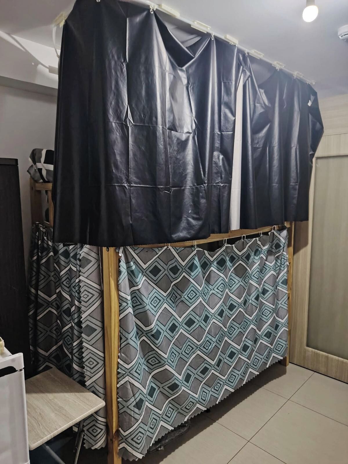 A room with a bed covered in a patterned bedspread, a small table, and a chair.