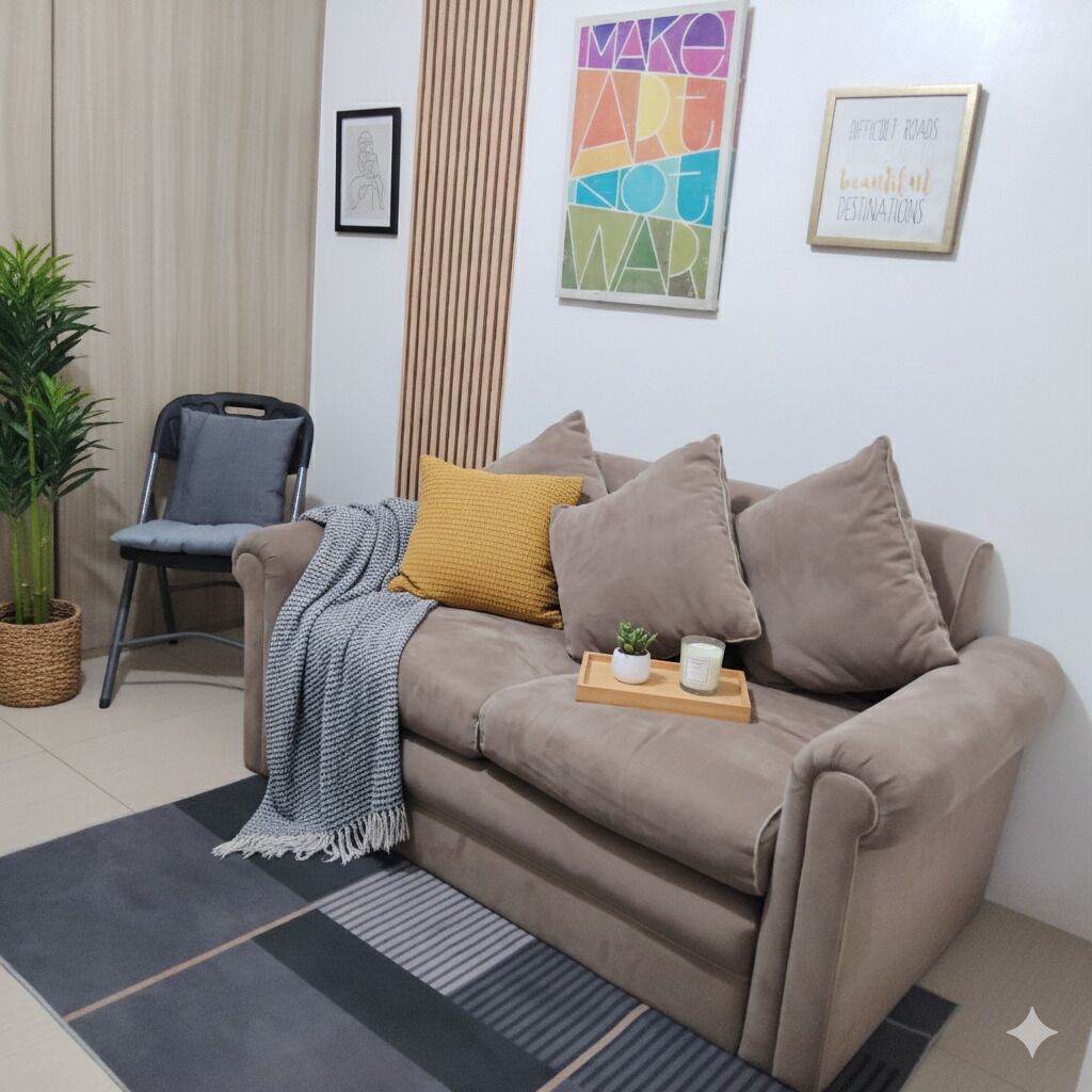 Un salon moderne avec un canapé beige, une petite table d’appoint, une plante en pot et une œuvre d’art encadrée accrochée au mur.