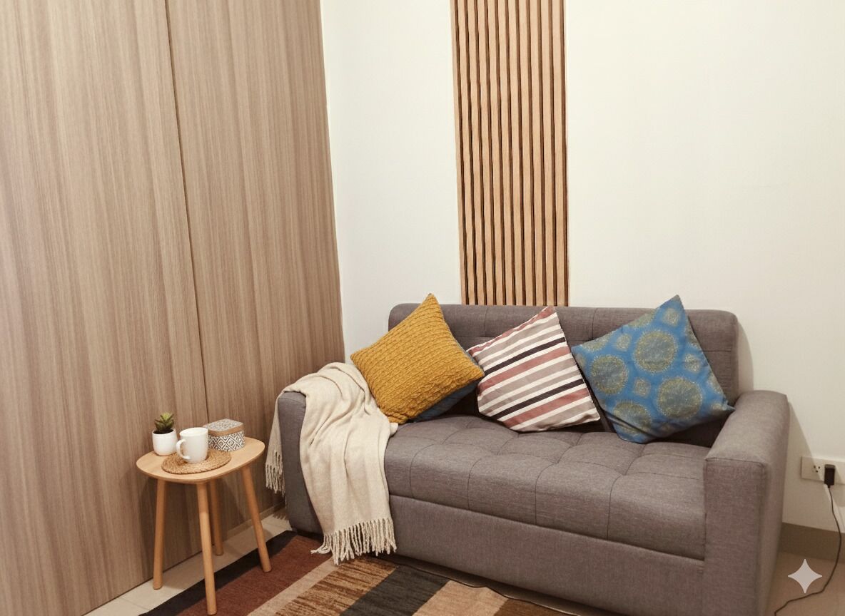 A grey sofa with patterned cushions, a small wooden side table with a plant, a white mug, and a woven placemat.