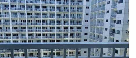 A high-rise building with multiple balconies and a pool area visible at the bottom.