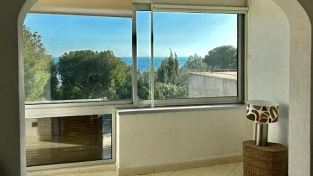 A room with a large window, a view of the sea, a chair, and a small table with a lamp. - Large Apartment With VIEW OF THE SEA AND CAP Canaille - free parking (Cassis)