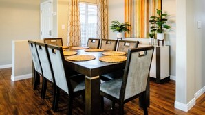 A dining area with a dark wooden table and chairs, woven placemats, and a modern pendant light. - 5 Bedroom House in Beautiful SW Bakersfield - HWY 99 Access (Bakersfield)