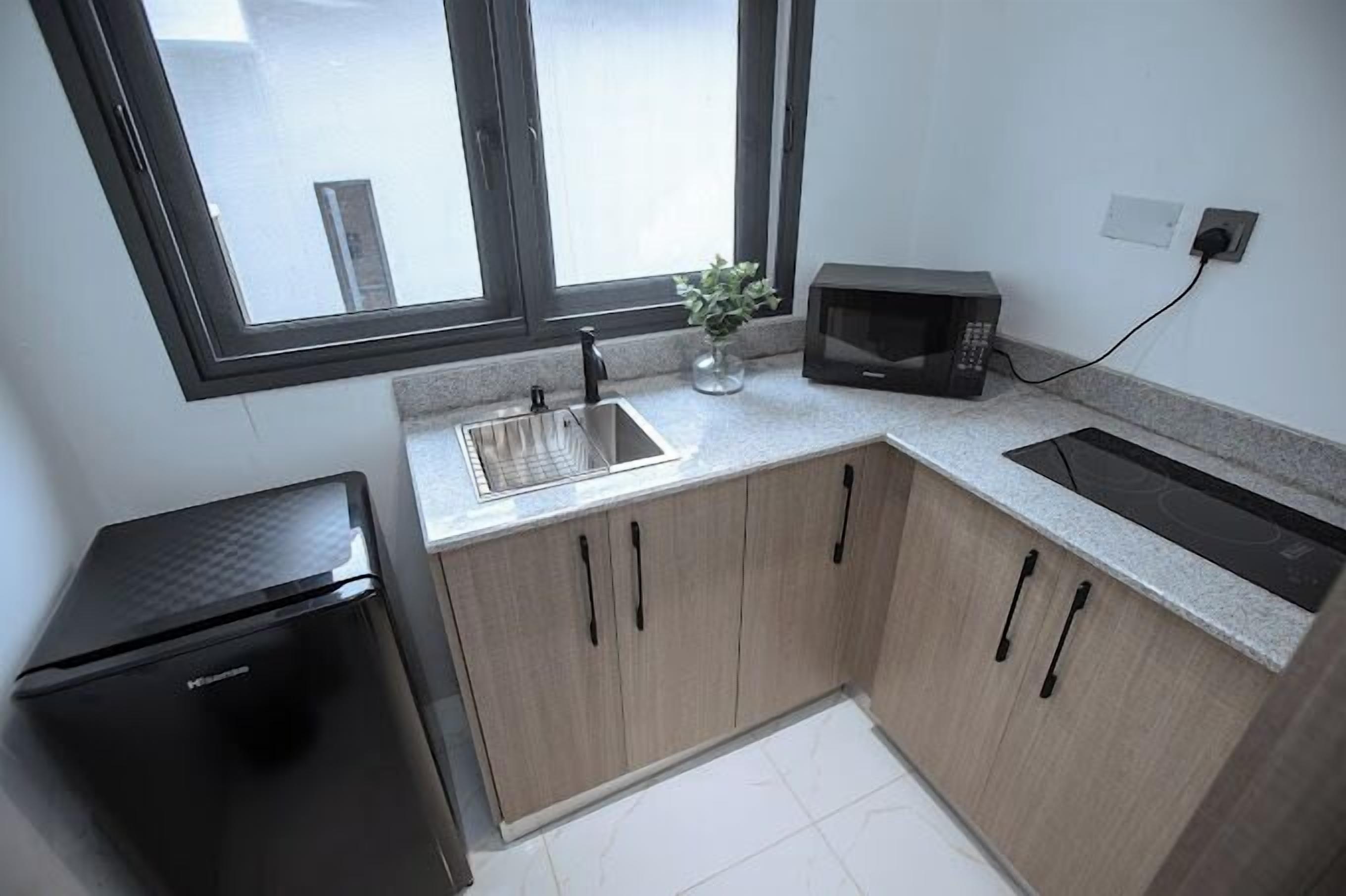 A compact kitchen with a refrigerator, microwave, sink, and stove.