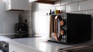 A kitchen with a black toaster on a countertop, a kettle, and a microwave.