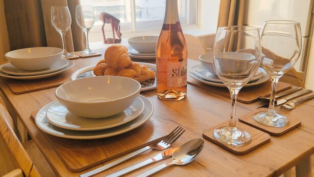 A dining table set with plates, bowls, wine glasses, and cutlery.