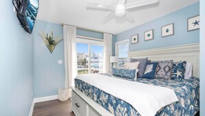 A bedroom with a bed, a ceiling fan, a window, and a view of the outside.