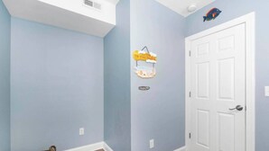 A room with light blue walls, a white door, and a small basket by the wall.