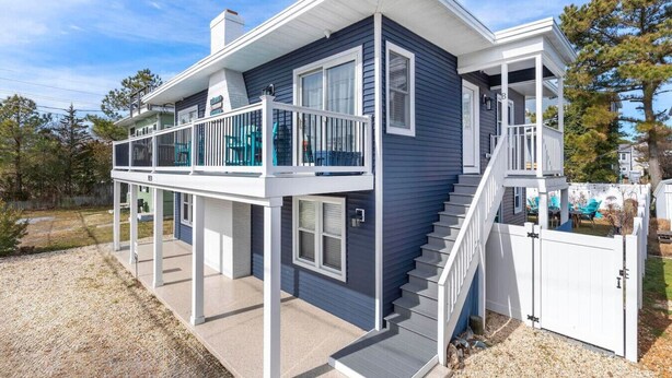 A two-story house with a balcony, a staircase, and a fenced yard.