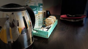 A kitchen area with a coffee maker, water bottles, a mug, and a tray with tea bags. - Cozy Beachside Stay Near Mahabalipuram Monuments. (Mahabalipuram)
