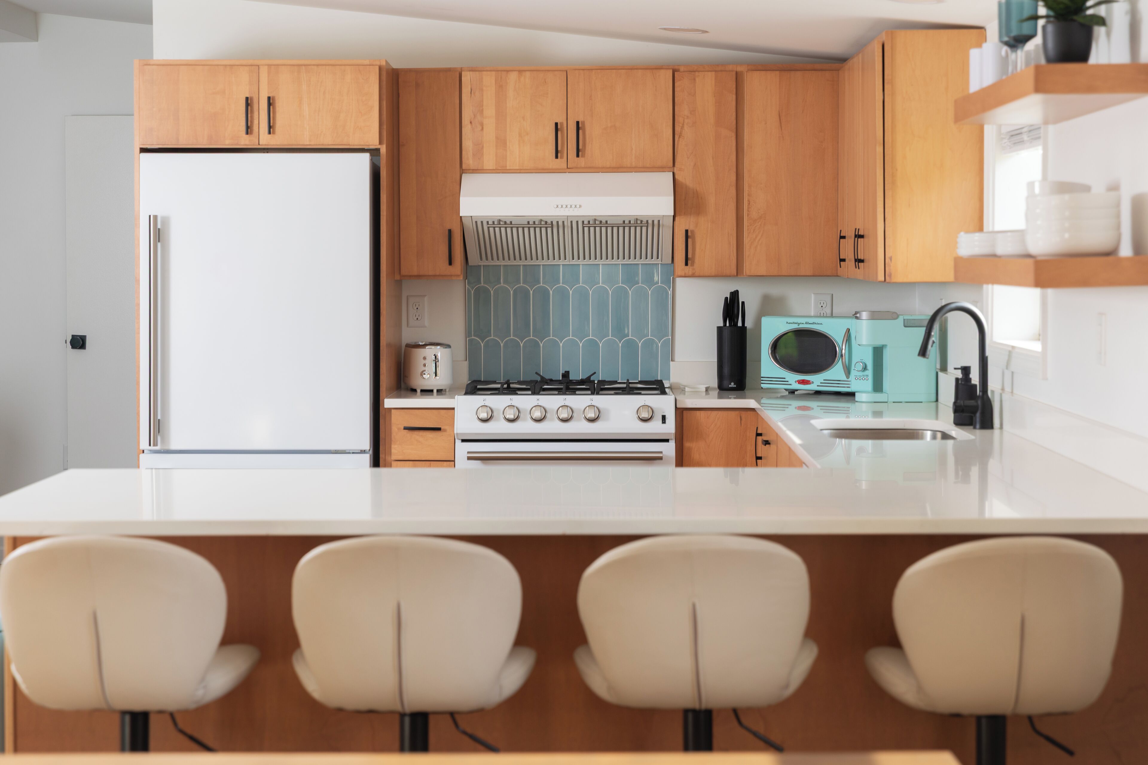 Una cocina moderna con armarios de madera, un refrigerador blanco, una estufa y un lavamanos.