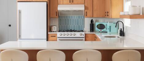 Una cocina moderna con armarios de madera, un refrigerador blanco, una estufa y un lavamanos.