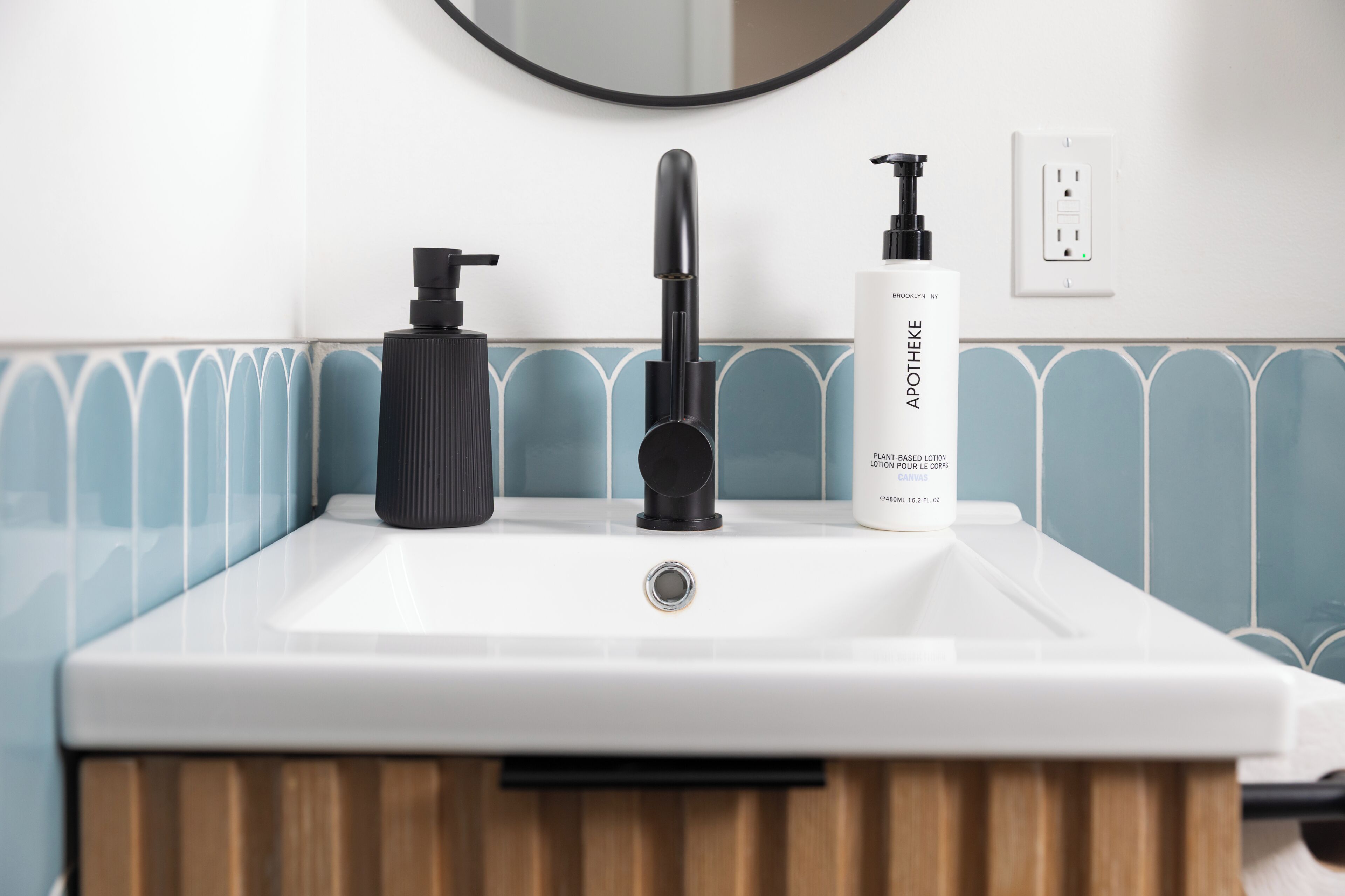 Un lavabo de salle de bain avec un robinet noir, un distributeur de savon noir et un flacon de lotion.