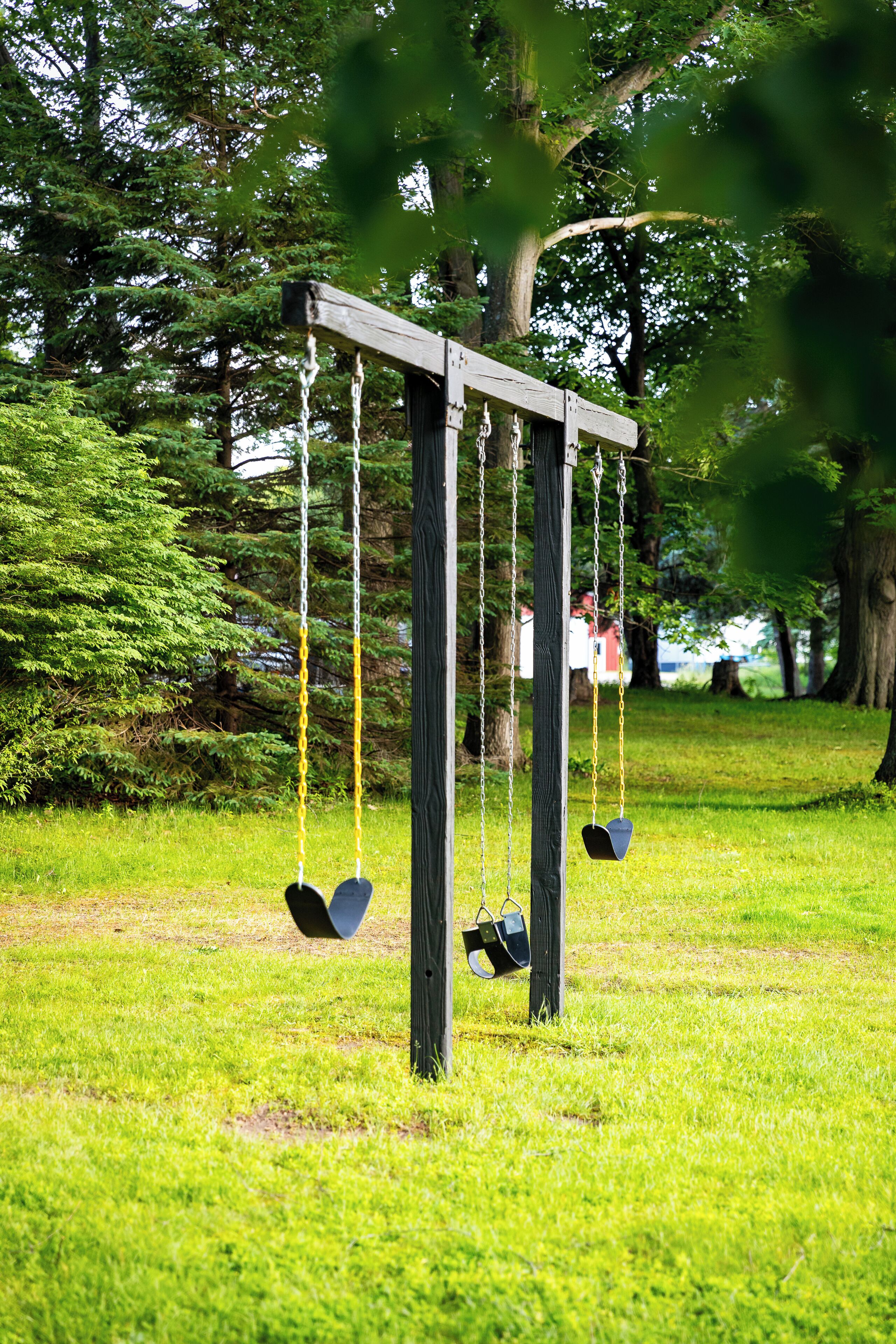 Une balançoire dans un parc, avec un poteau en bois et des chaînes.
