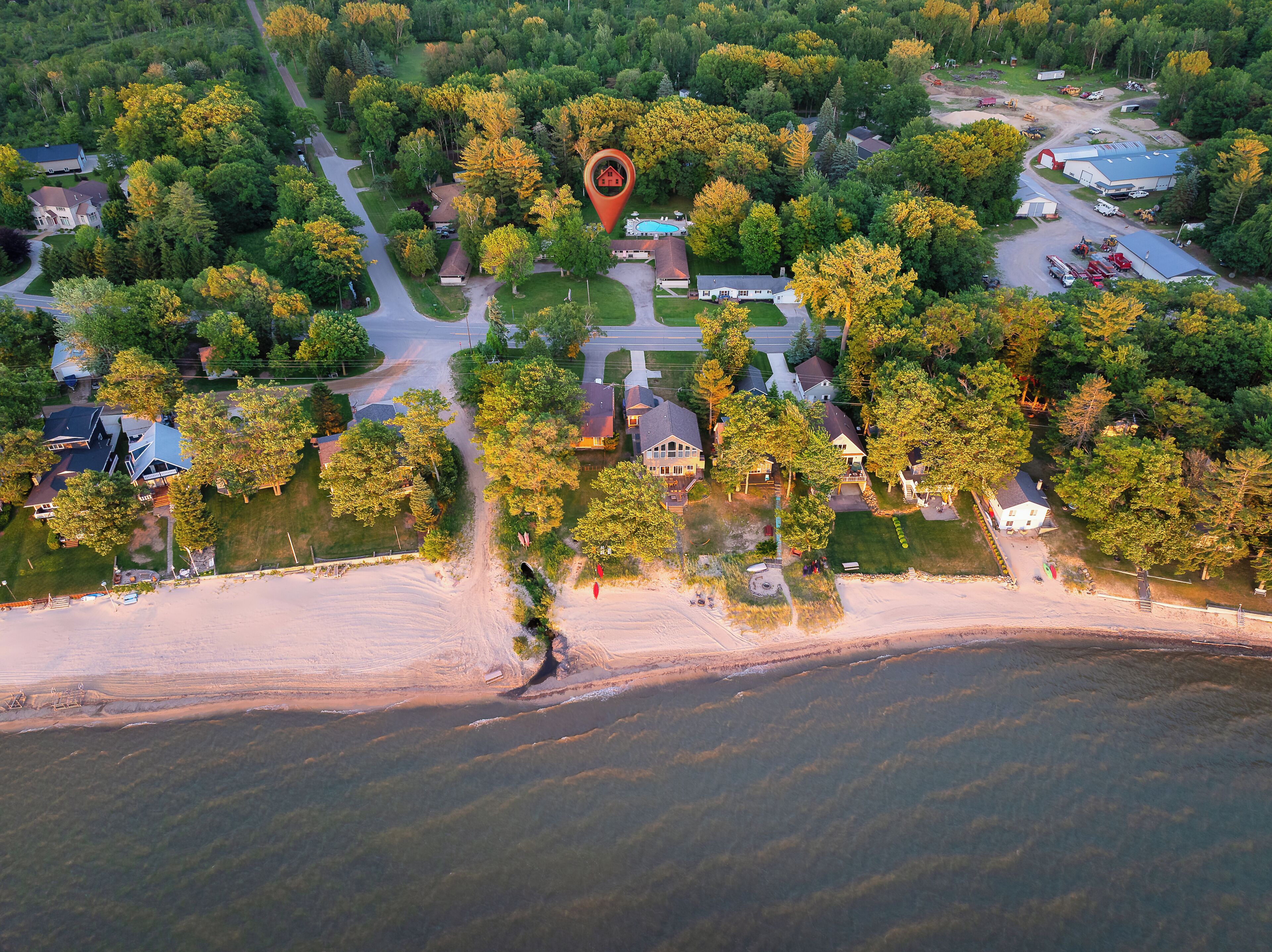 Vue aérienne d’un quartier résidentiel avec des maisons, une piscine et une plage.