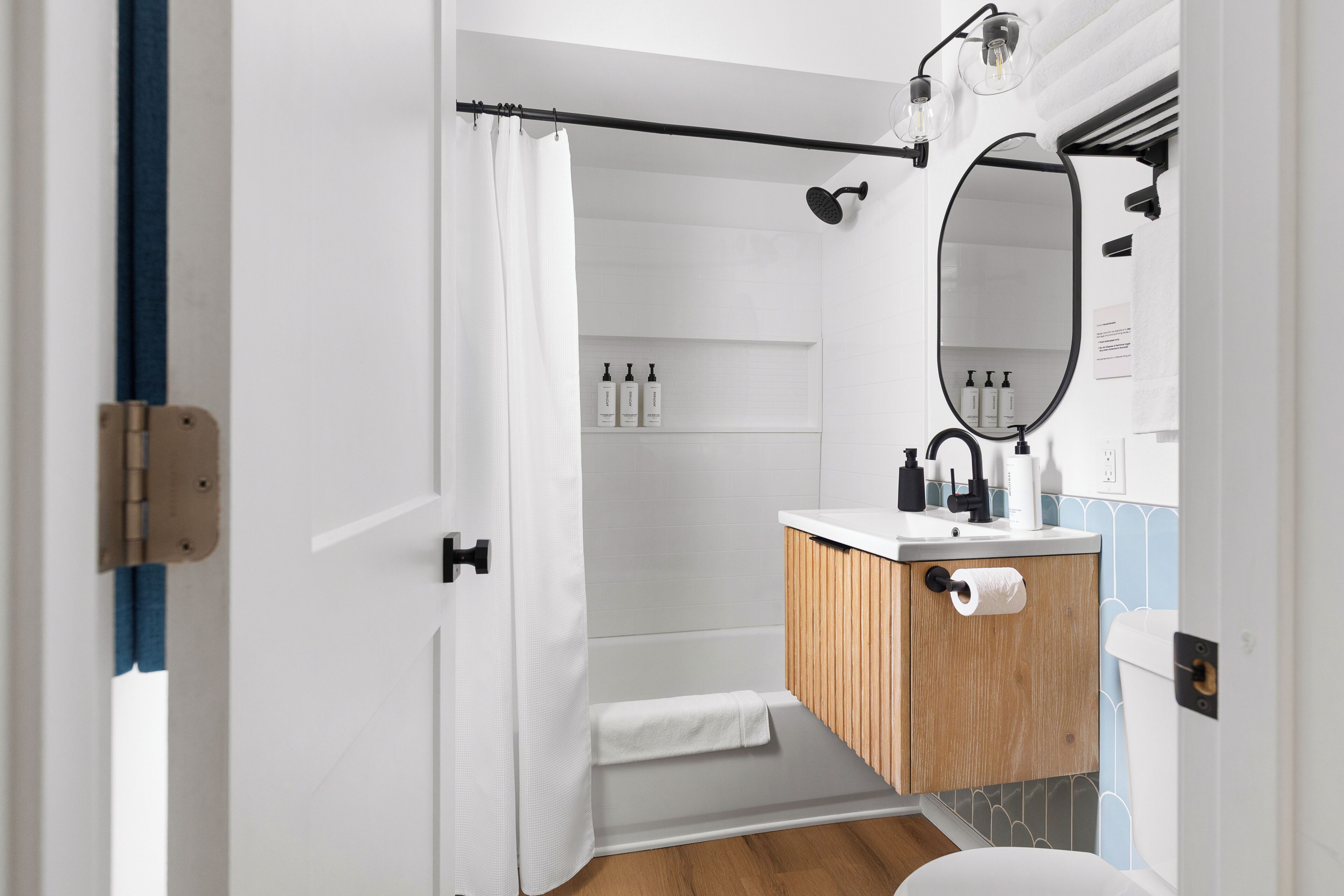 A bathroom with a shower, toilet, sink, and mirror.