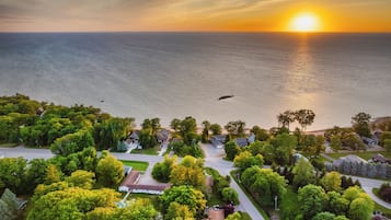 Vue aérienne d’un quartier résidentiel avec des maisons, des routes et une étendue d’eau, prise au coucher du soleil.